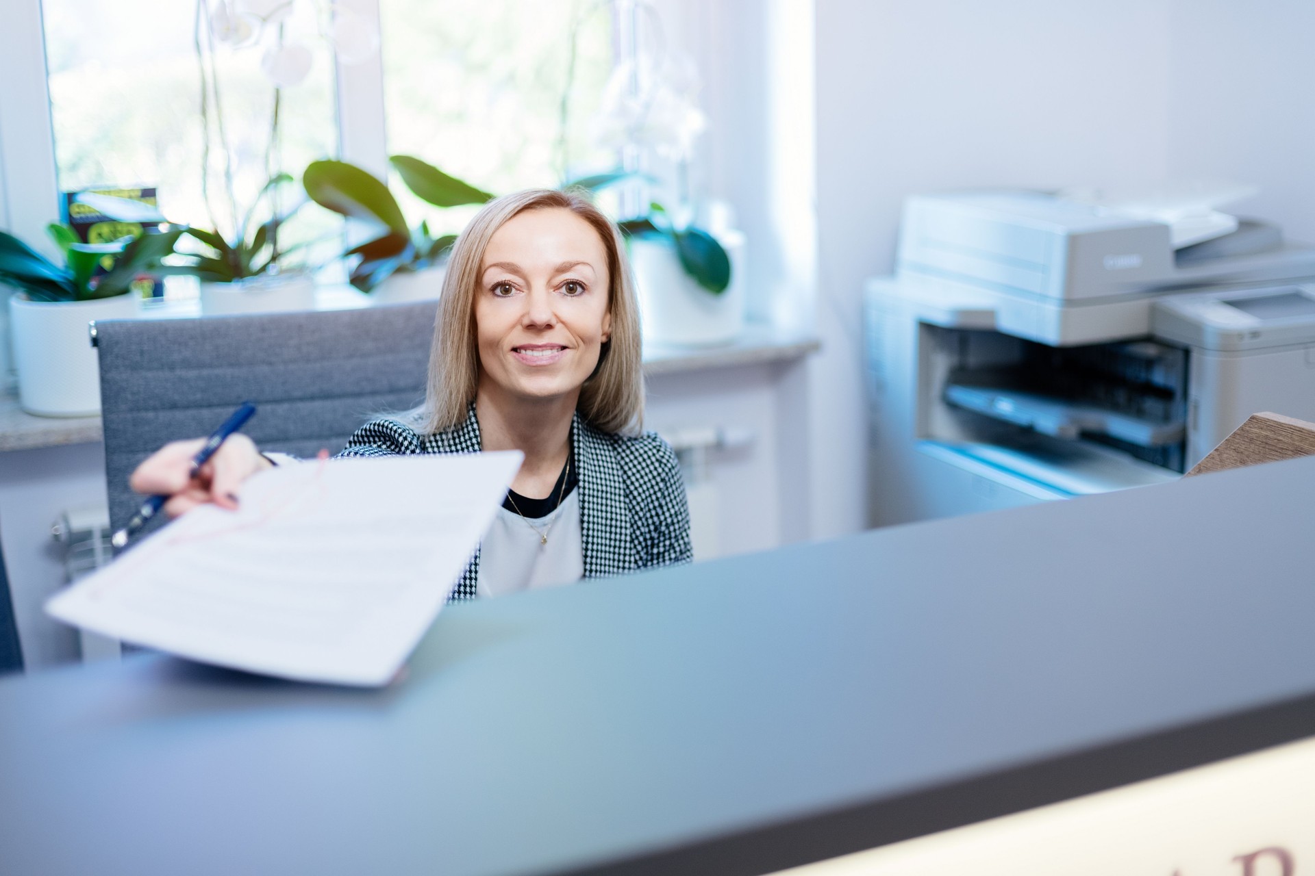 A nice, smiling woman at the reception desk, office, notary office gives the documents